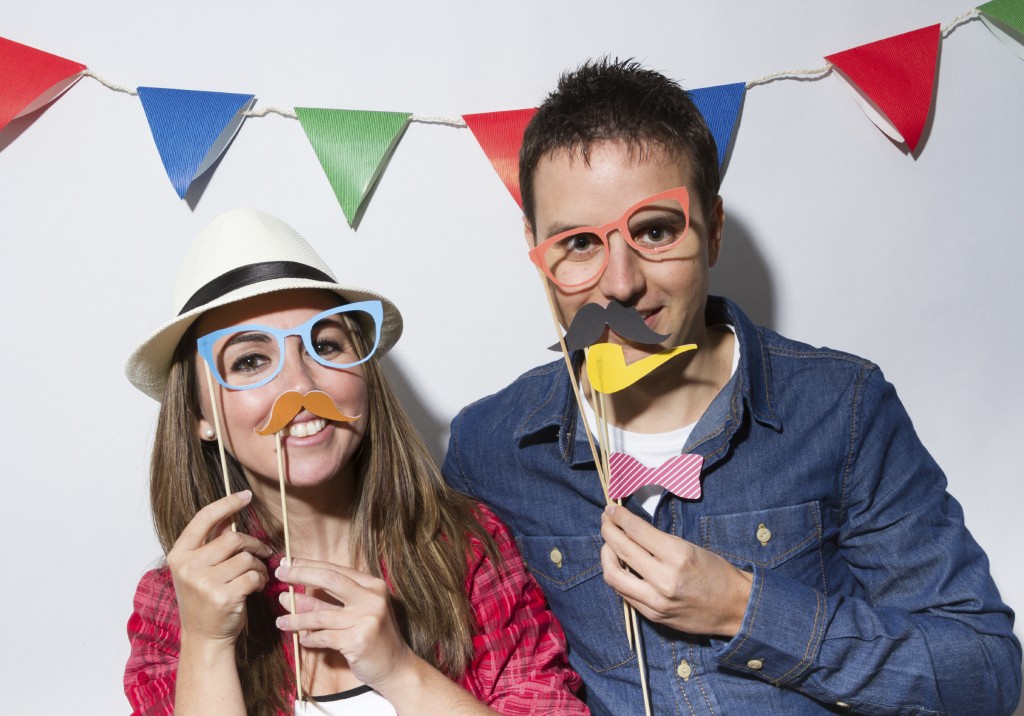 Young couple in a Photo Booth party with garland decoration background